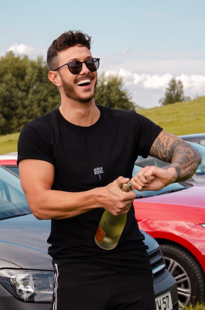 Vrolijke jonge man met een fles champagne in zijn handen. Afbeelding is puur decoratief.